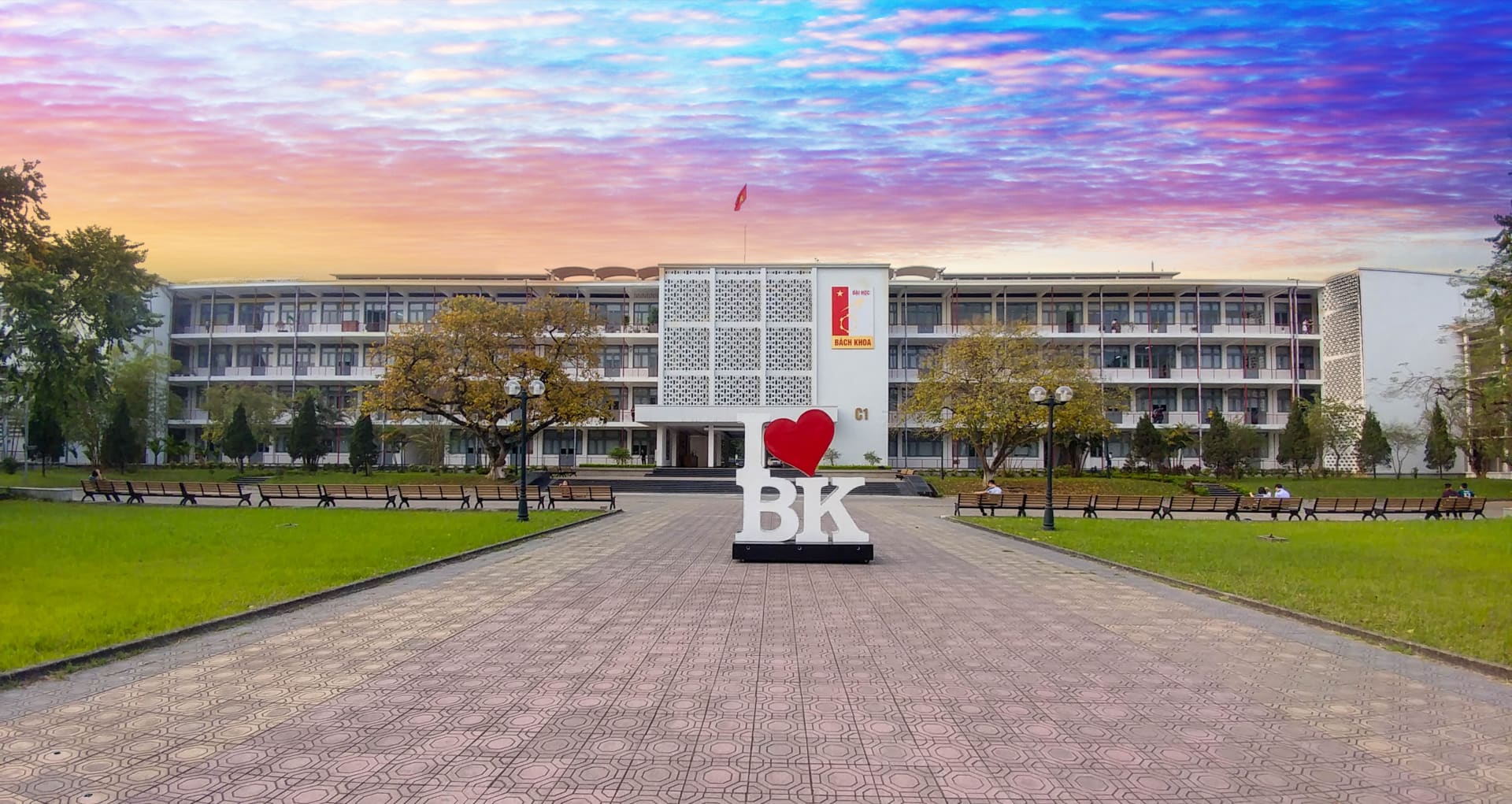 Quảng trường trước toà C1 lúc hoàng hôn, biểu tượng chữ BK và trái tim đỏ đặt giữa lối đi lát gạch.